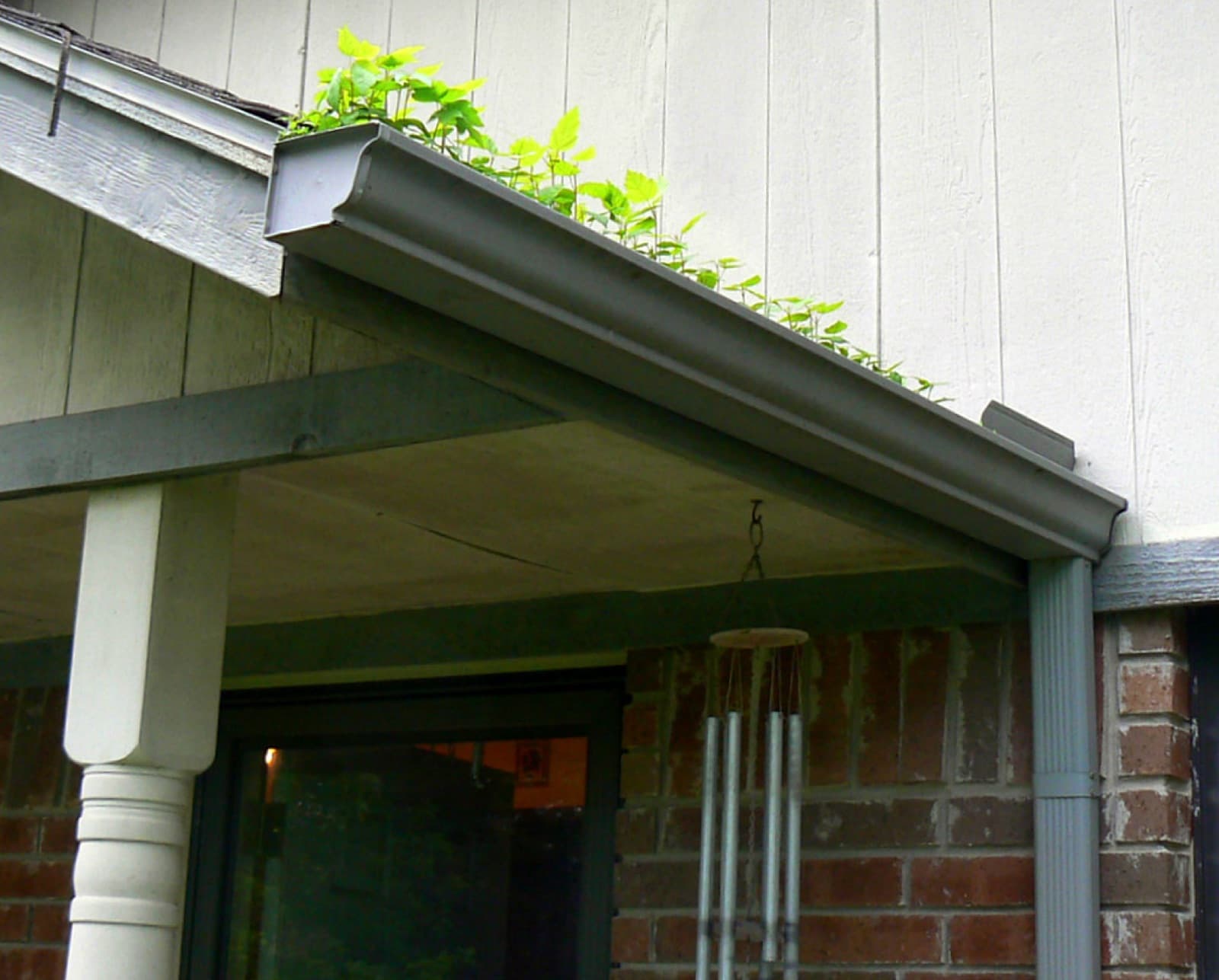 A rain gutter clogged with debris on a house, in need of cleaning