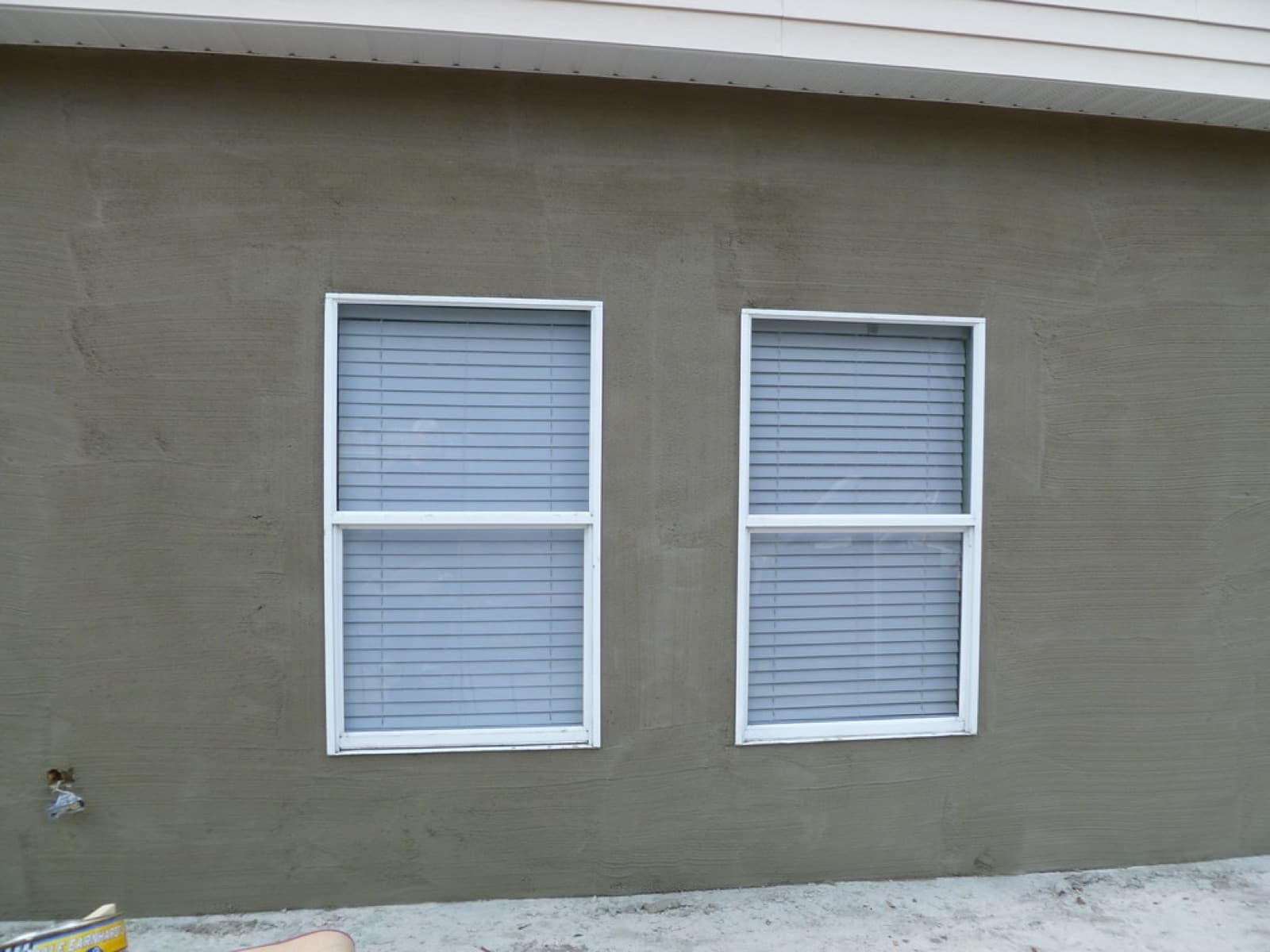 The stucco exterior wall of a home with two windows